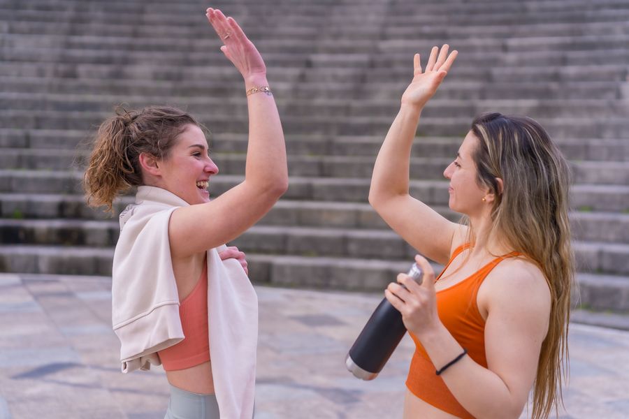 dwie kobiety przybijające piątkę po wysiłku fizycznym, na tle schodów